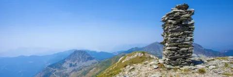 Aufschichtung von Steinen steht am Gipfel in einer Berglandschaft unter blaue Himmel