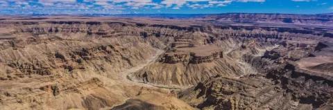 Große Schluchtenlandschaft mit hohen Felsen und tiefer Schlucht unter leicht bewölktem Himmel