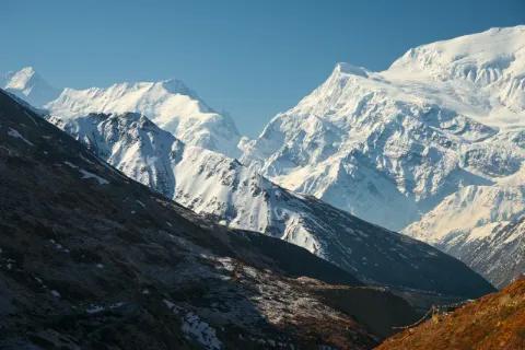 Bergpanorama mit dunklem Berghang umringt von schneebedeckten Bergen