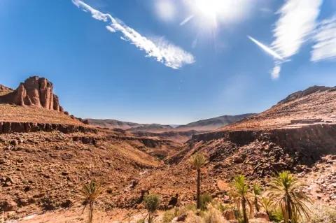 Blick über eine steinige, rote Ebene mit steinigen Erhebungen. Der Himmel über der Ebene ist blau.