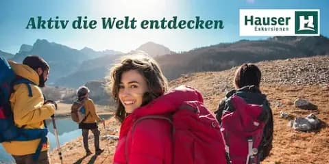 Eine Frau in einer roten Softshell-Jacke, die Teil einer Wandergruppe ist, lächelt in die Kamera.