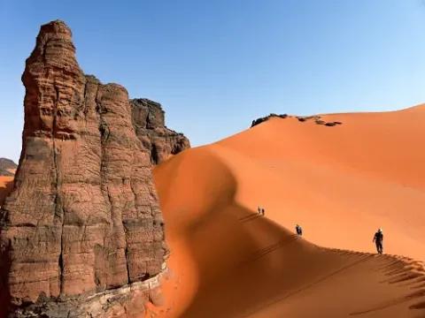 Man sieht eine Gruppe beim Dünenwandern durch den Tadrart in Algerien.