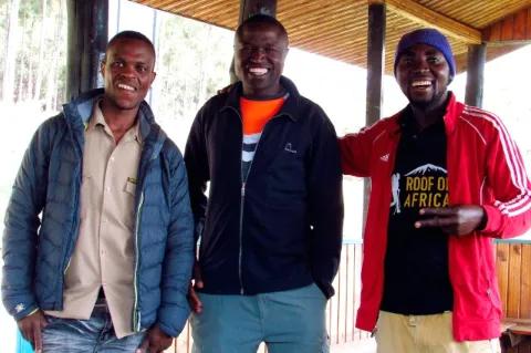 Drei Männer stehen nebeneinander, schauen in die Kamera und lächeln.