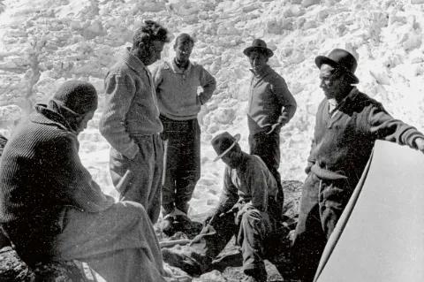 Eine Gruppe Bergsteiger stehen im Kreis und besprechen sich