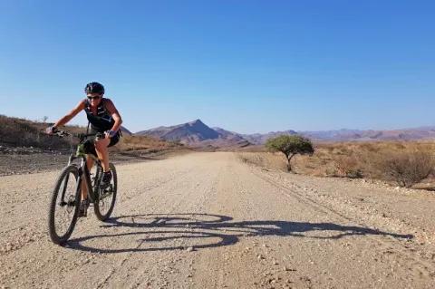 Eine Frau auf einem Mountainbike fährt durch eine trockene Steppenlandschaft