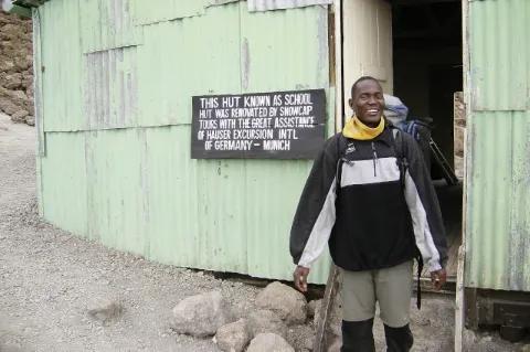 Ein Mensch verlässt ein grünes Gebäude mit Wellblech.