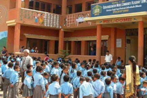 Eine Gruppe von Schülerinnen und Schülern in Schuluniform steht vor einem orangenen Schulgebäude.