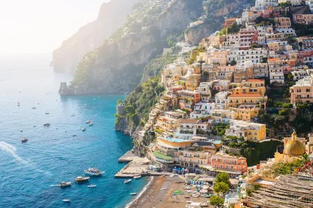 Bunte Häuser an den Hängen einer Steilküste mit Strand und Meer im Vordergrund