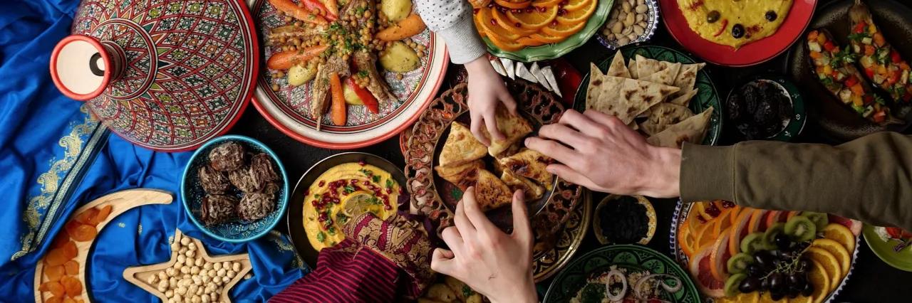 Ein Tisch von oben der mit einer Vielzahl arabischer Gerichte und buntem Geschirr in orientalischen Farben bedeckt ist.