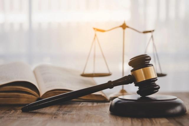 Richterhammer, Buch und Waage stehen auf einem Holztisch