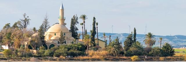 Moschee am Wasser umrundet von grüner Vegetation unter bewölktem Himmel