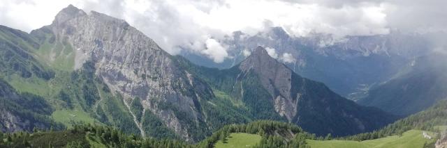 Blick auf die felsige Hügellandschaft der karnischen Alpen, über denen weiße Wolken schweben.