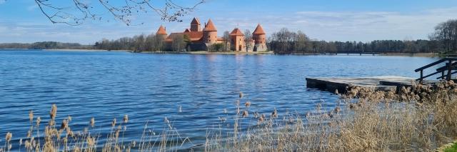 Blick vom Ufer eines blauen Sees auf eine Insel mit einer Burg