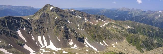 Karge Berglandschaft mit einzelnen Schneefeldern unter blauem Himmel