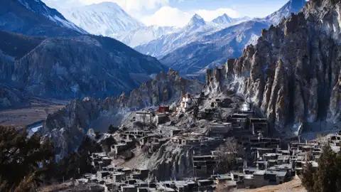 Traditionelles Bergdorf im Himalaya, umgeben von beeindruckender Berglandschaft.