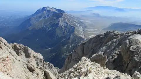Aussicht von einem Berggipfel auf weitere Berge und ein Tal.