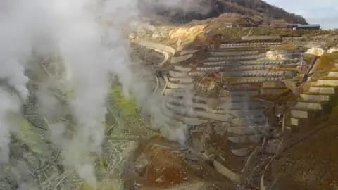 Vulkanische Aktivität mit Dampf und terrassierten Hängen.