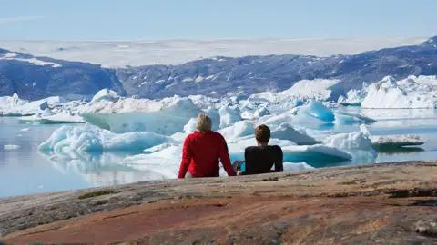 Campingplatz mit Zelten und Eisbergen im Hintergrund.