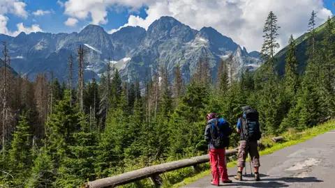 Zwei Wanderer mit Rucksäcken bewundern die Berglandschaft während ihrer Wanderung.