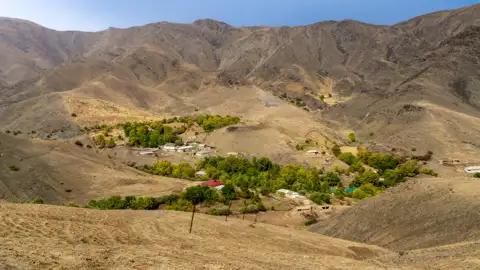 Blick auf ein abgelegenes Bergdorf in einer trockenen Landschaft.