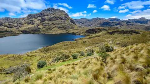 Panoramablick auf einen Bergsee und die umliegende Hügellandschaft.