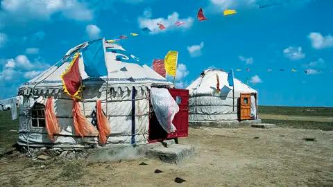 Zwei Jurten dienen als Unterkunft, geschmückt mit traditionellen Fahnen.