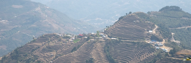 Blick auf eine grüne, hügelige Landschaft mit grünen Terrassenfeldern und einzelnen Dörfern
