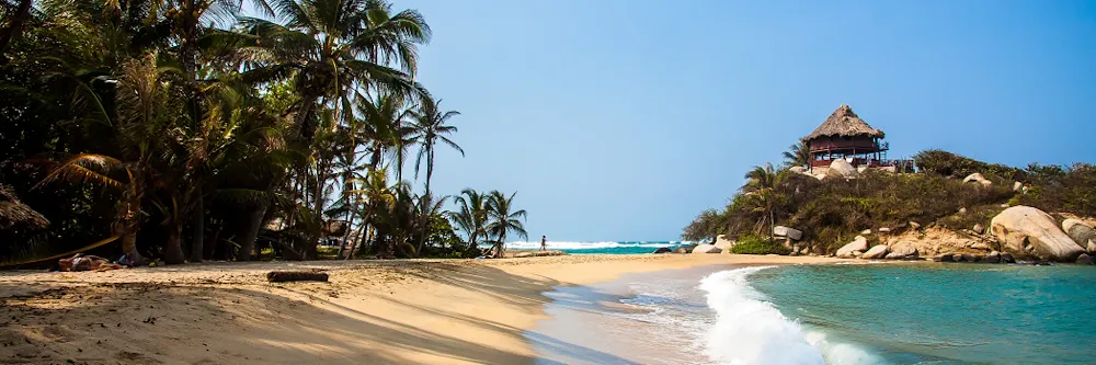 Palmengesäumter Sandstrand, Meer und kleinem bewachsenem Hügel mit einer Hütte