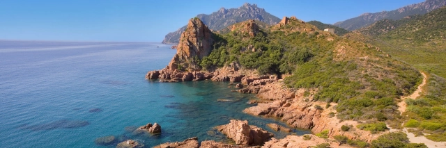 Die felsige und grün bewachsene Küste Baia di Gairo am klaren Meer von Sardinien. 