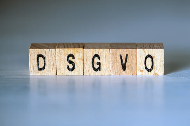 Fünf Holzwürfel mit den Buchstaben DSGVO auf blauem Hintergrund