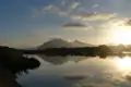 Sonnenaufgang über einem See, die Berge spiegeln sich im Wasser.
