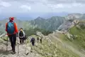 Wandergruppe auf einem Bergpfad inmitten einer Berglandschaft.