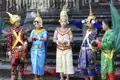 Kambodschanische Tänzer in traditionellen Kostümen posieren vor einer Tempelanlage.