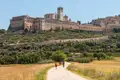 Wanderer auf einem Weg, der zur Basilika San Francesco in Assisi führt.