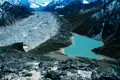 Gletscherlandschaft im Himalaya mit einem türkisfarbenen See. Ein Wanderer befindet sich im Vordergrund und erkundet die Umgebung.