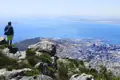 Panoramablick auf Kapstadt vom Tafelberg. Der Reisende steht auf felsigem Gelände und betrachtet die Stadt und das Meer.