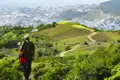 Wanderer auf einem Bergpfad mit Blick auf eine Stadt mit blauen Gebäuden.