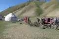 Mountainbiker legen eine Pause während ihrer Tour ein. Sie stehen mit ihren Fahrrädern vor einer Jurte, die vermutlich als Unterkunft dient. Ein Begleitfahrzeug ist ebenfalls zu sehen.