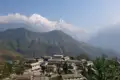 Panoramablick auf ein traditionelles nepalesisches Bergdorf mit den majestätischen schneebedeckten Gipfeln des Himalayas im Hintergrund.