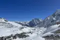 Panorama einer verschneiten Bergkette unter blauem Himmel.