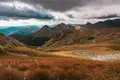 Herbstliche Berglandschaft unter dramatischem Himmel.