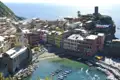 Luftbild von Vernazza, einem der fünf Dörfer der Cinque Terre in Italien. Bunte Häuser säumen den Hafen mit Booten im Vordergrund.