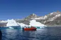Bootstour in der Nähe eines Eisbergs mit Blick auf die Berge.