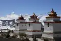 Drei Chortens mit Gebetsfahnen vor einer Bergkette im Himalaya.