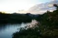 Abendlicher Blick auf den Fluss, umgeben von Bäumen und Hügeln im Hintergrund.