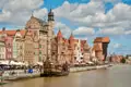 Blick auf die historische Architektur der Danziger Altstadt, darunter das Krantor und ein im Hafen liegendes Schiff.