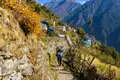 Wanderer auf einem Bergpfad in Nepal, umgeben von Bergdörfern und der beeindruckenden Kulisse des Himalayas.