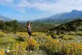 Reisender fotografiert eine Berglandschaft mit gelben Wildblumen.