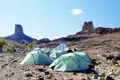Campingplatz in der Wüste mit Zelten und Felsformationen im Hintergrund.