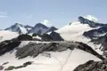 Wandergruppe auf einem schneebedeckten Bergpfad mit Gletscher im Hintergrund.